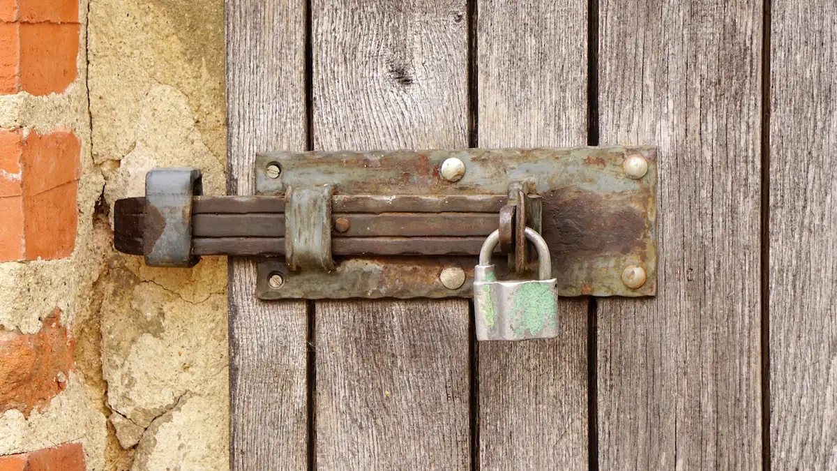 Vorhängeschloss von vorne an alter Tür mit Riegel