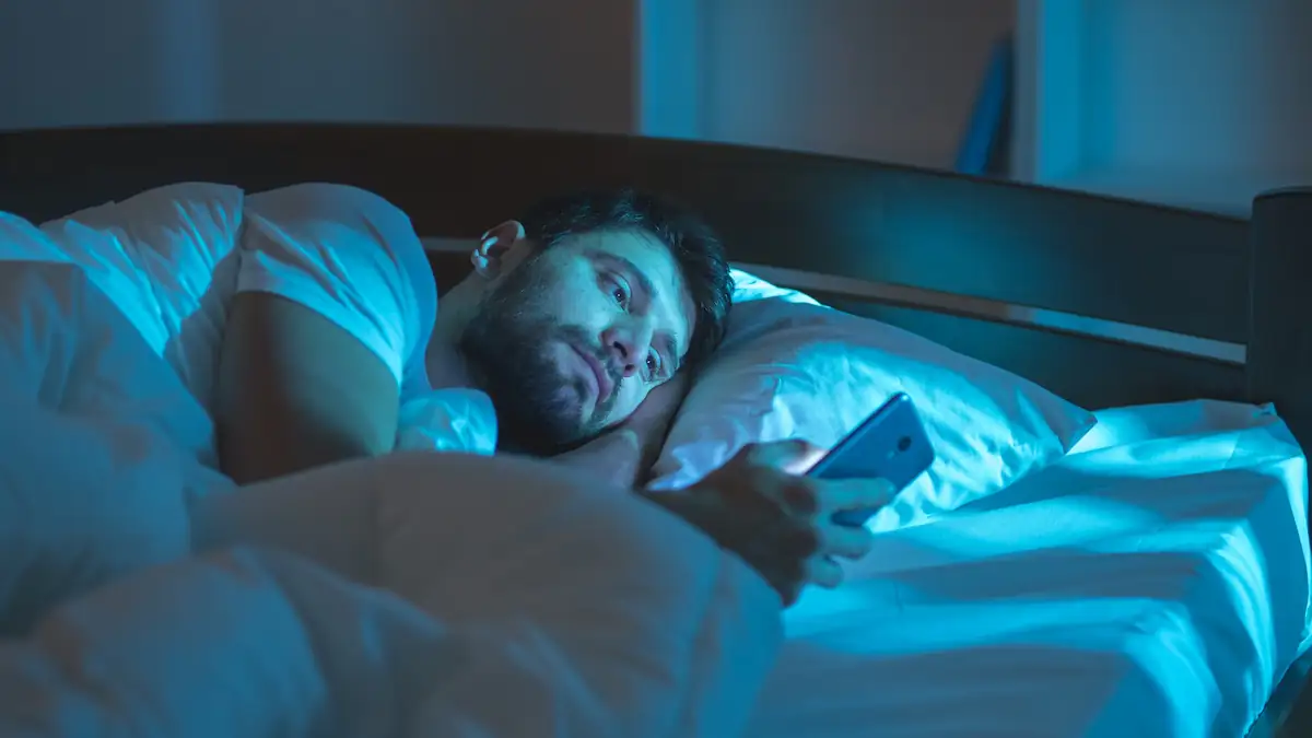 Online-Dating-Burnout Symbolbild: Mann liegt mit Smartphone im Bett
