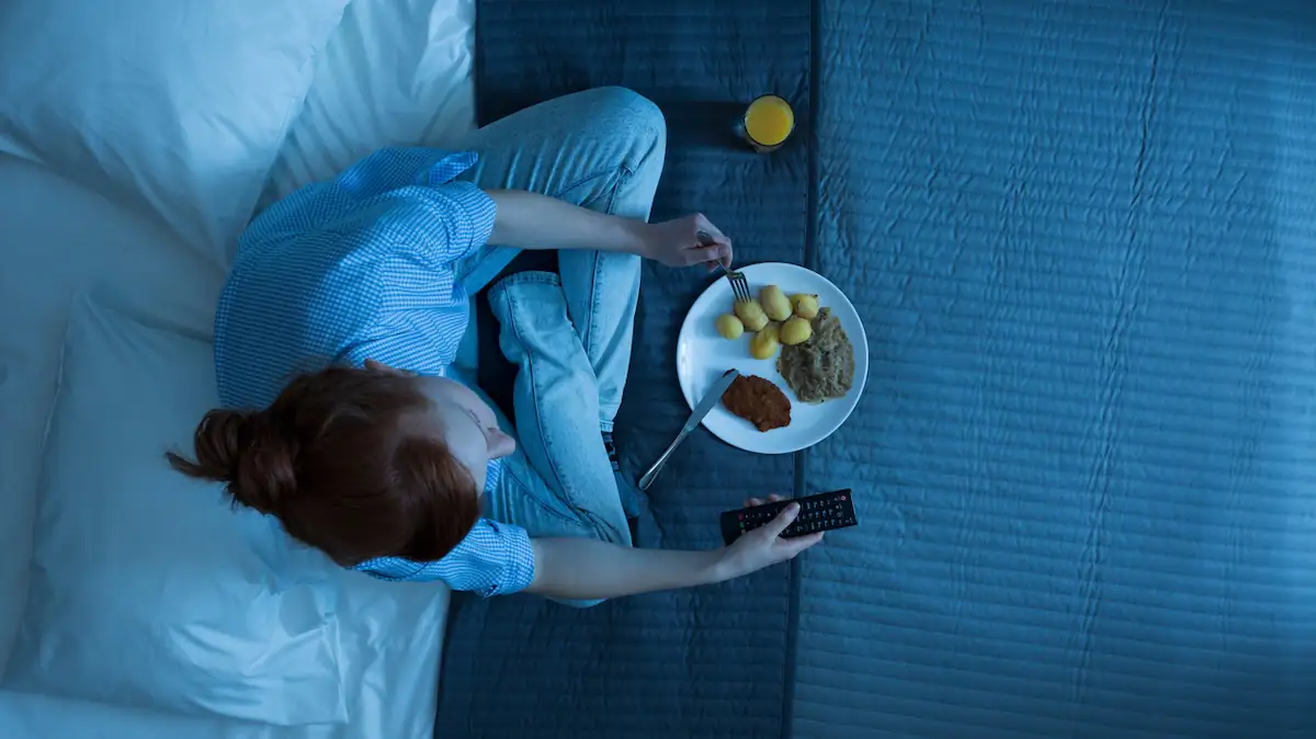 Frau isst nachts im Bett