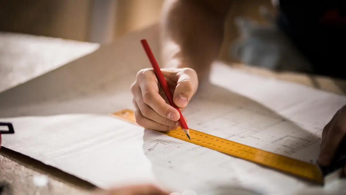 jemand zeichnet eine Linie an einem Lineal entlang auf einem Architektenplan