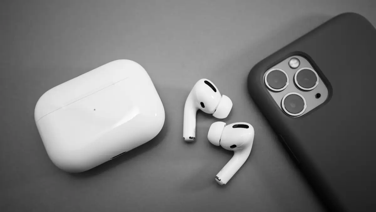 AirPods Pro 2 liegen neben ihrem Case und einem iPhone in schwarzer Hülle