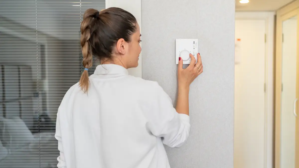 Frau dreht Heizung über zentrale Steuerung auf