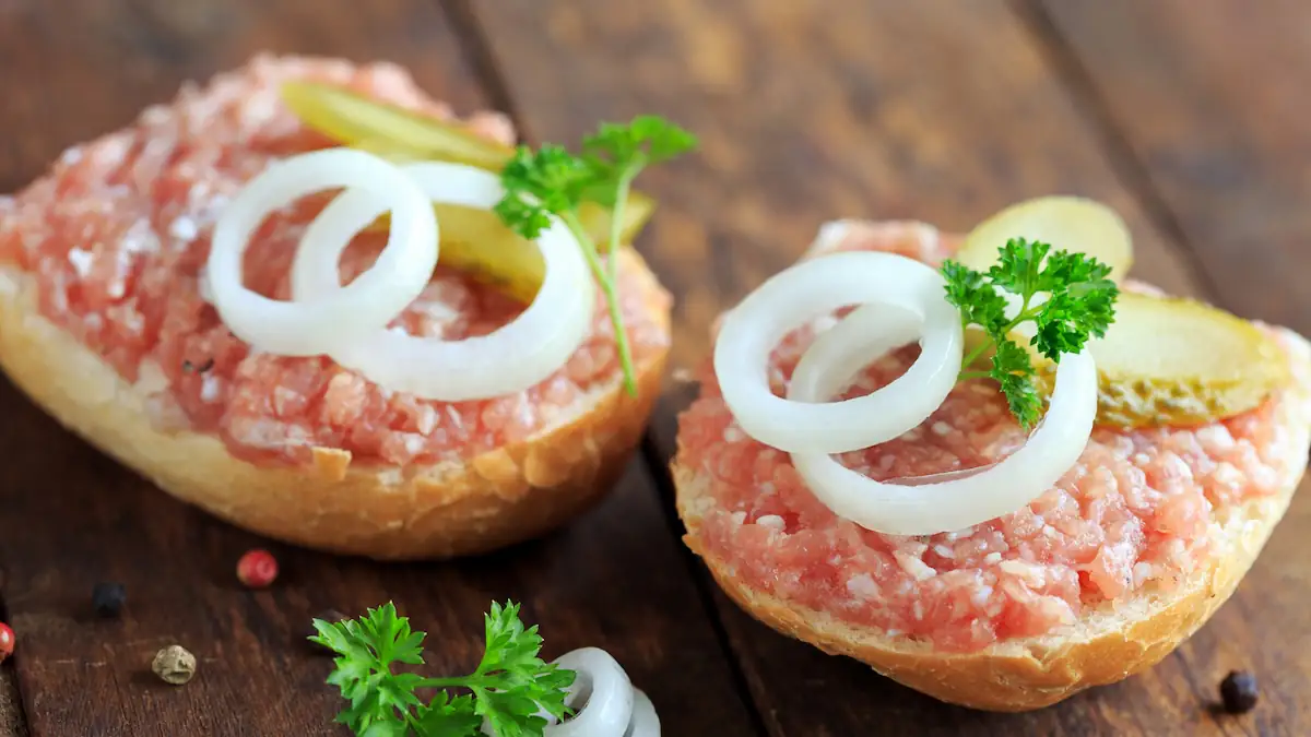 Fleisch in Form von Mett auf einem Brötchen mit Zwiebeln und Petersolie