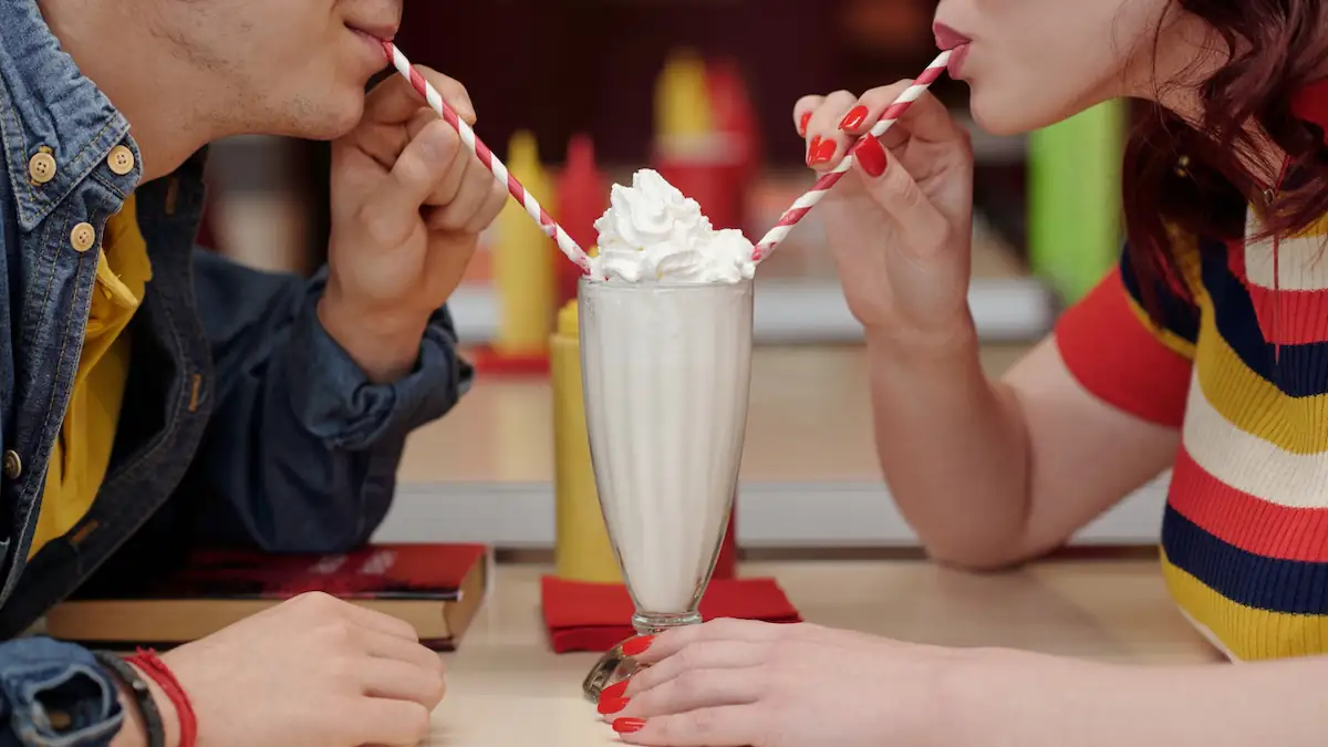 Junges Paar trinkt zusammen einen Milchshake mit zwei Strohhalmen