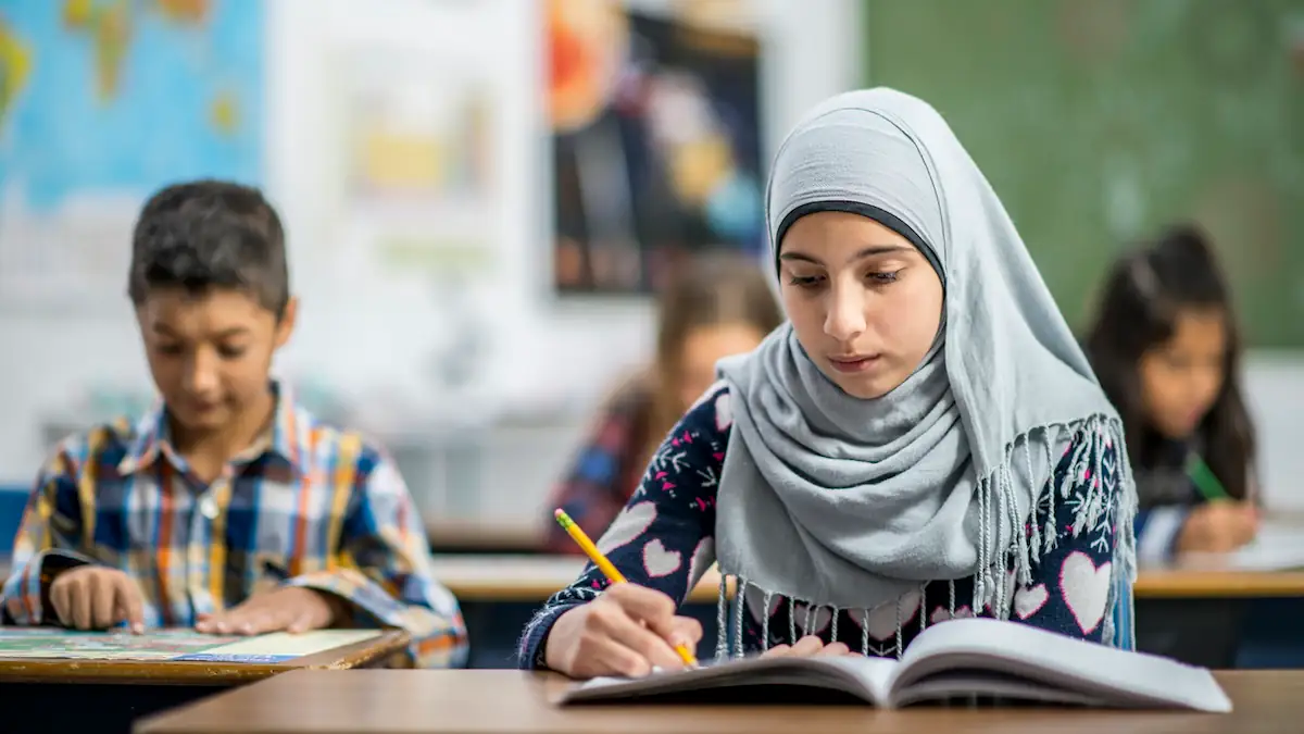 Feiertag Muslime: Junges Mädchen mit Kopftuch nimmt in einer Schule am Unterricht teil