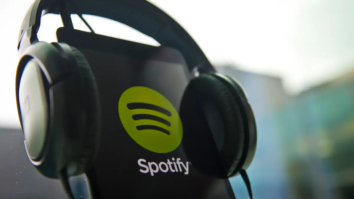 Smartphone mit Spotify-Logo, auf dem Gerät sitzt ein paar Over-Ear-Kopfhörer
