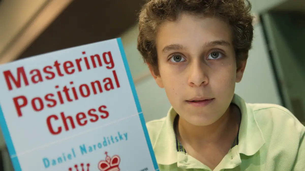Daniel Naroditsky als Kind mit einem Buch über Schach in der Hand