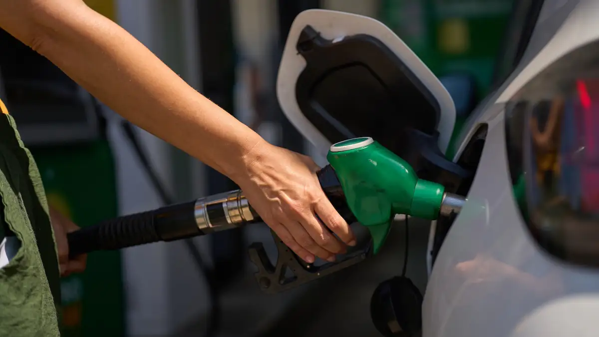 Frau tankt ihr weites Auto an einer Tankstelle mit einem grünen Zapfhahn