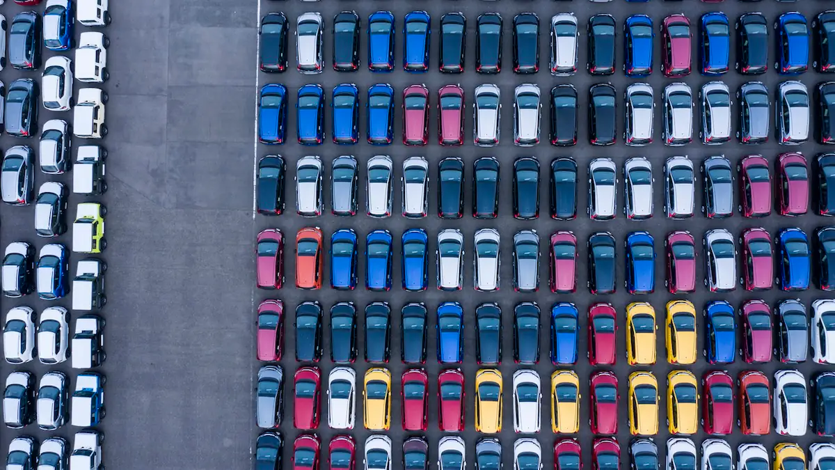 Autos in vielen verschiedenen Autofarben parken auf einem Parkplatz, das Ganze von oben fotografiert