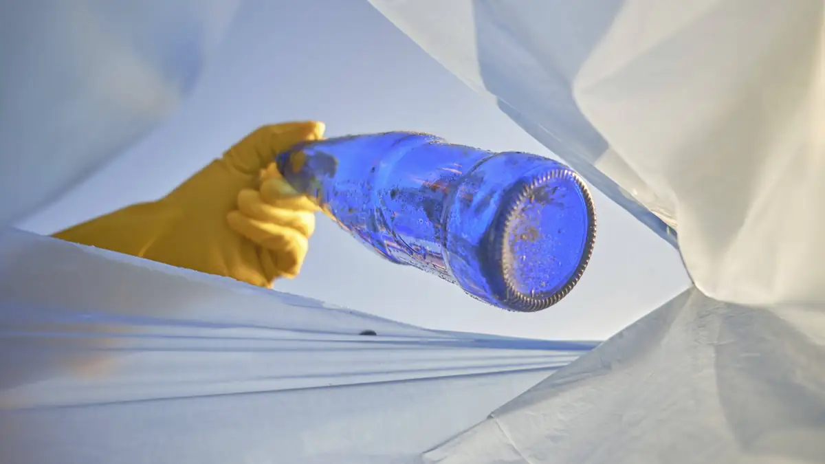 Jemand sammelt eine blaue Glasflasche auf