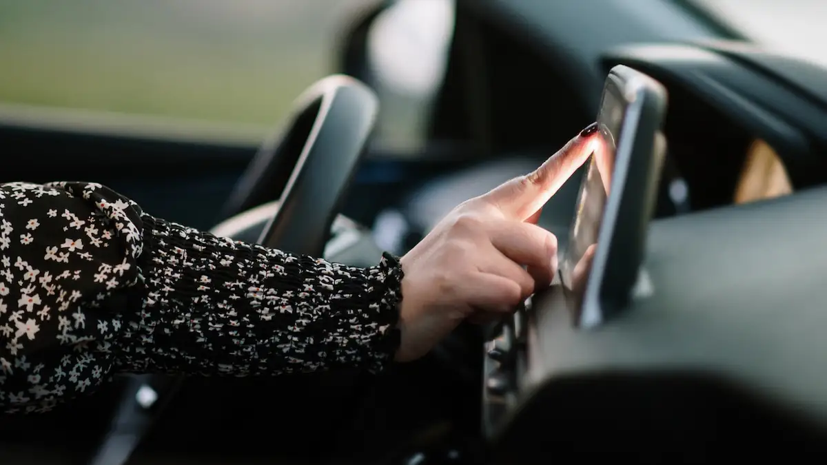 Frau steuert Scheibenwischer ihres Autos über einen Touchscreen
