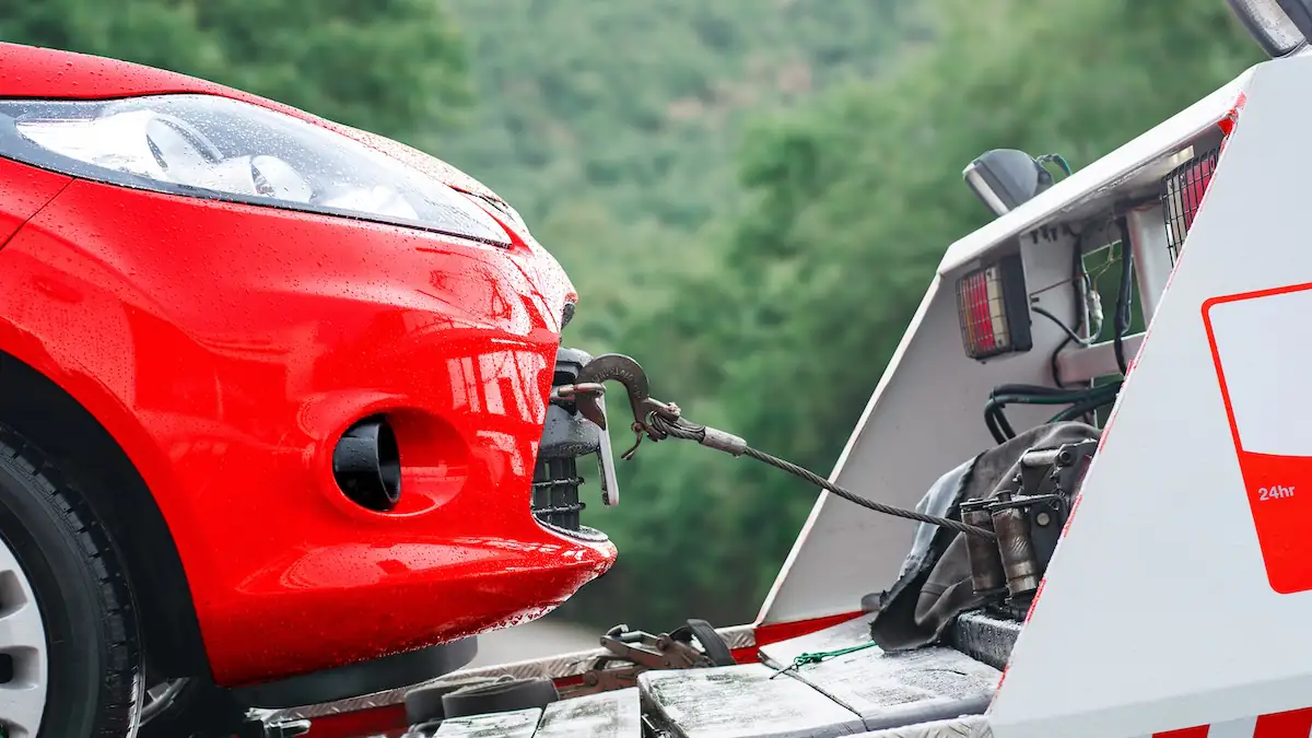 Abschleppöse hinter Autoklappe vorn: Rotes Auto wird abgeschleppt