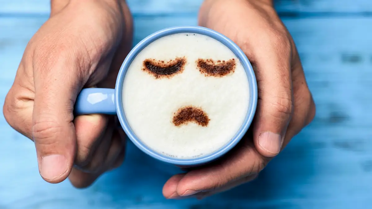 Blue Monday: Tasse mit Kaffee, auf dessen Milchschaum ein trauriges Gesicht gemalt wurde