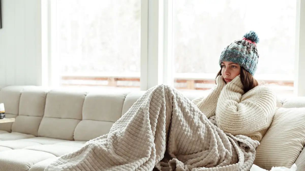 Frau sitzt frierend auf dem Sofa