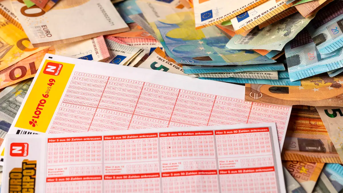 Lottoscheine liegen auf Geldscheinen