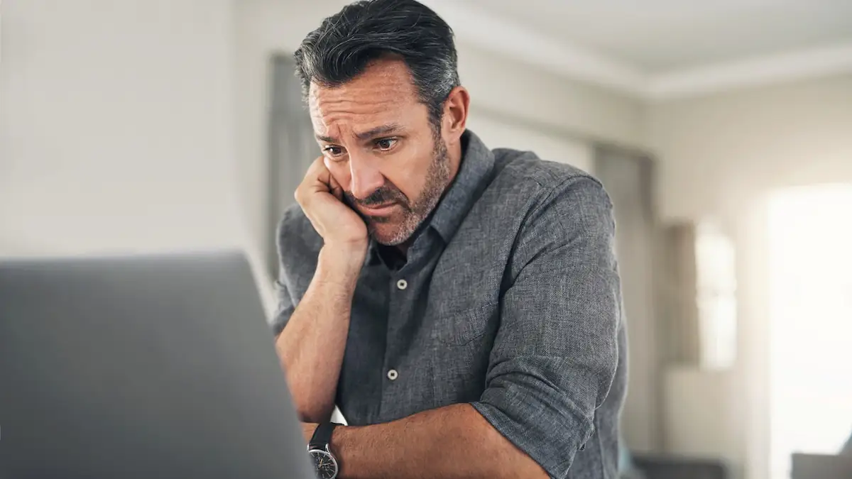 Mann schaut verärgert auf seinen Computer: Nachname „Null“ lässt Systeme abstürzen