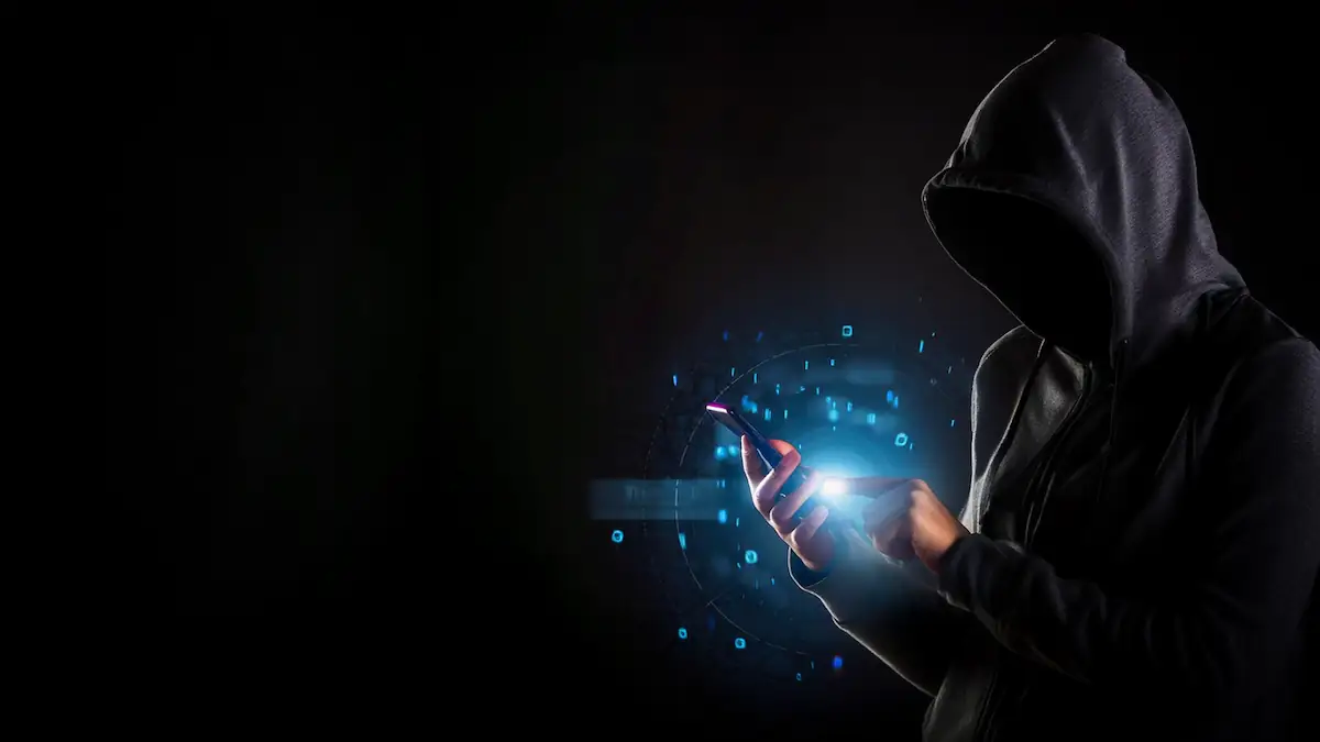 Stummer Anruf Warnung: Gestalt mit Kapuze hält ein leuchtendes Handy in der Hand