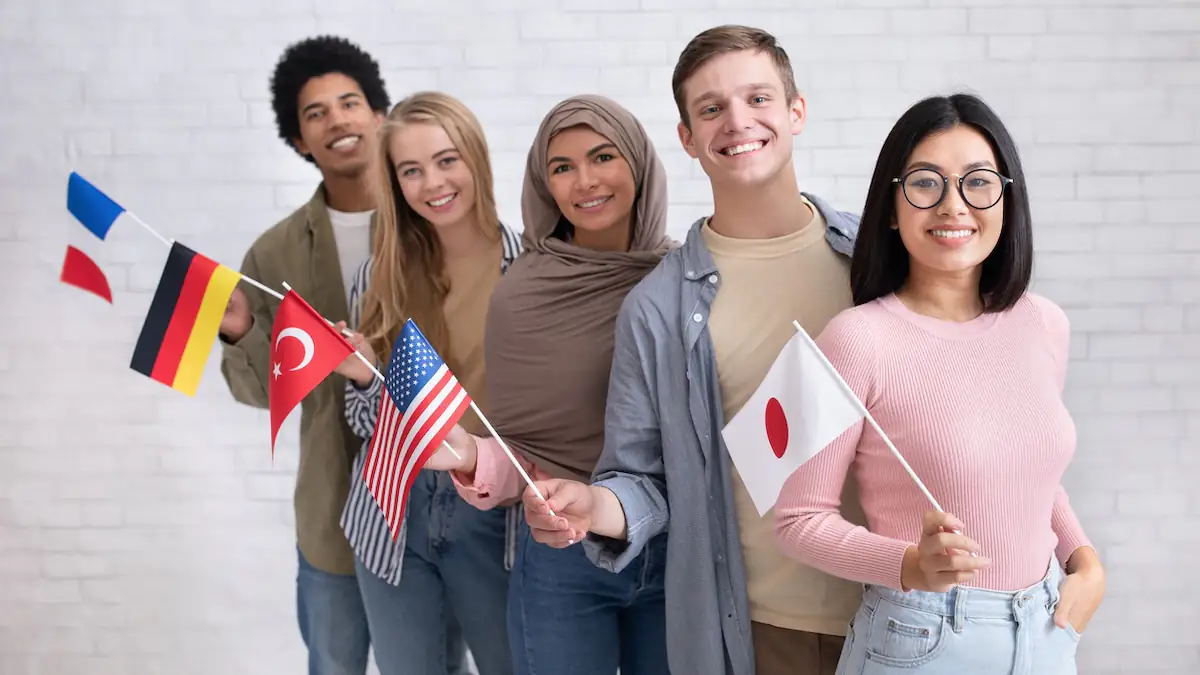 Wörter übersetzen: Mehrere junge Leute stehen nebeneinander, wobei jeder eine kleine Landesflagge in der Hand hält