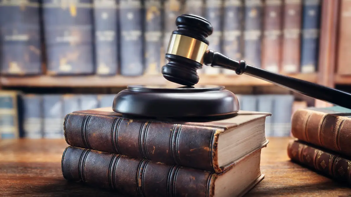 Gericht entscheidet zu Wohngeldantrag eines Langzeitstudenten: Gerichtshammer auf alten Büchern als Symbolbild