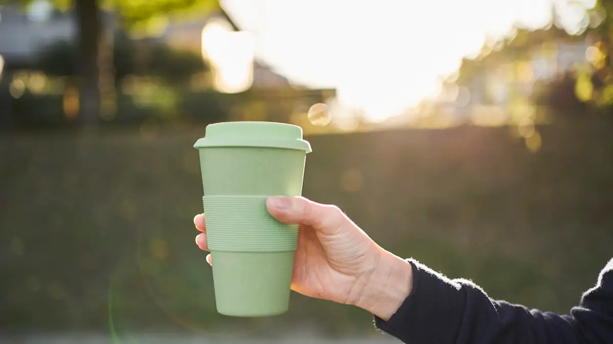 Jemand hält einen grünen Kaffeebecher hoch