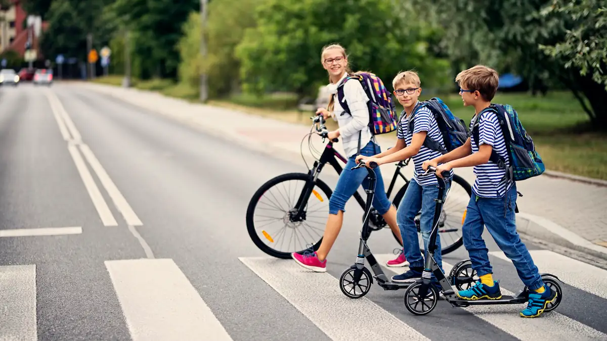 Kinder auf dem Schulweg gehen über einen Zebrastreifen
