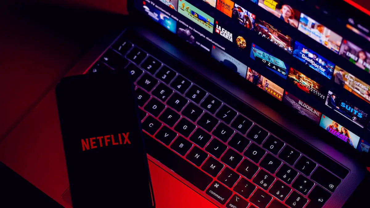 Smartphone mit Netflix-Logo liegt auf Laptop, der die Streaming-Plattform des Anbieters zeigt