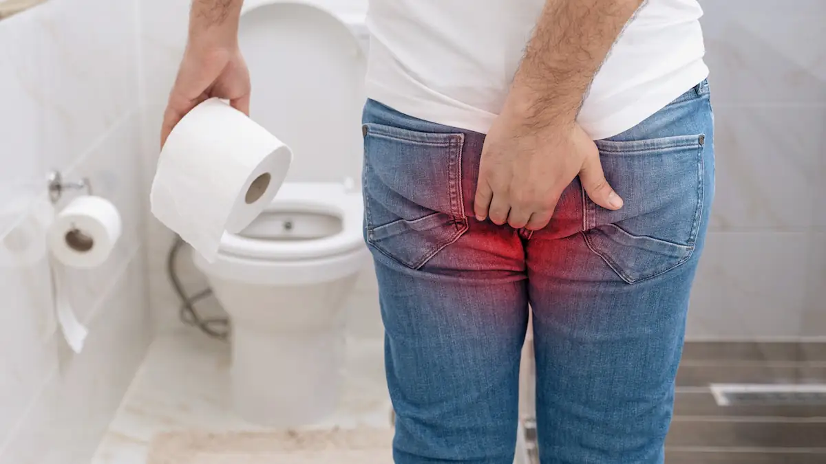 Mann steht mit Schmerzen vor einer Toilette: Symbolbild für Hämorrhoiden