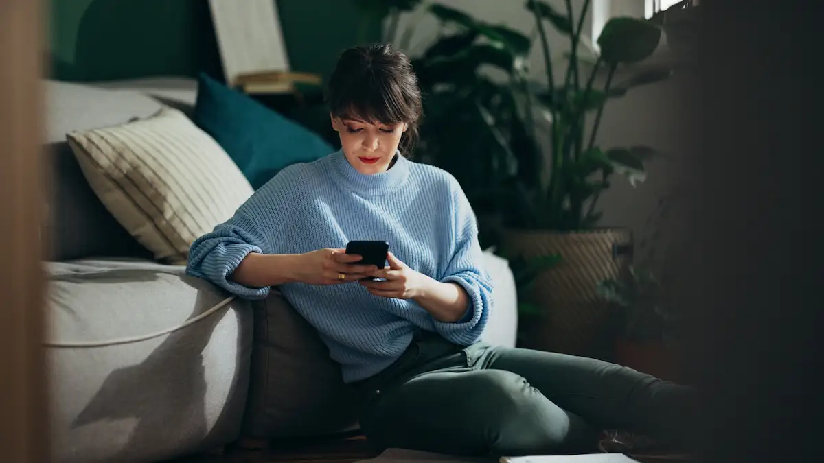 Anruf: Frau sitzt mit Smartphone auf dem Boden