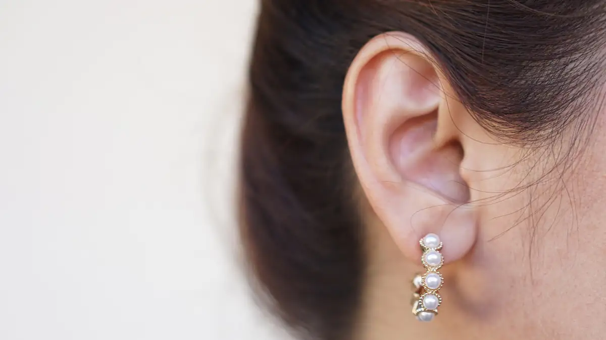 Dunkelhaarige Frau trägt einen Perlen-Ohrring