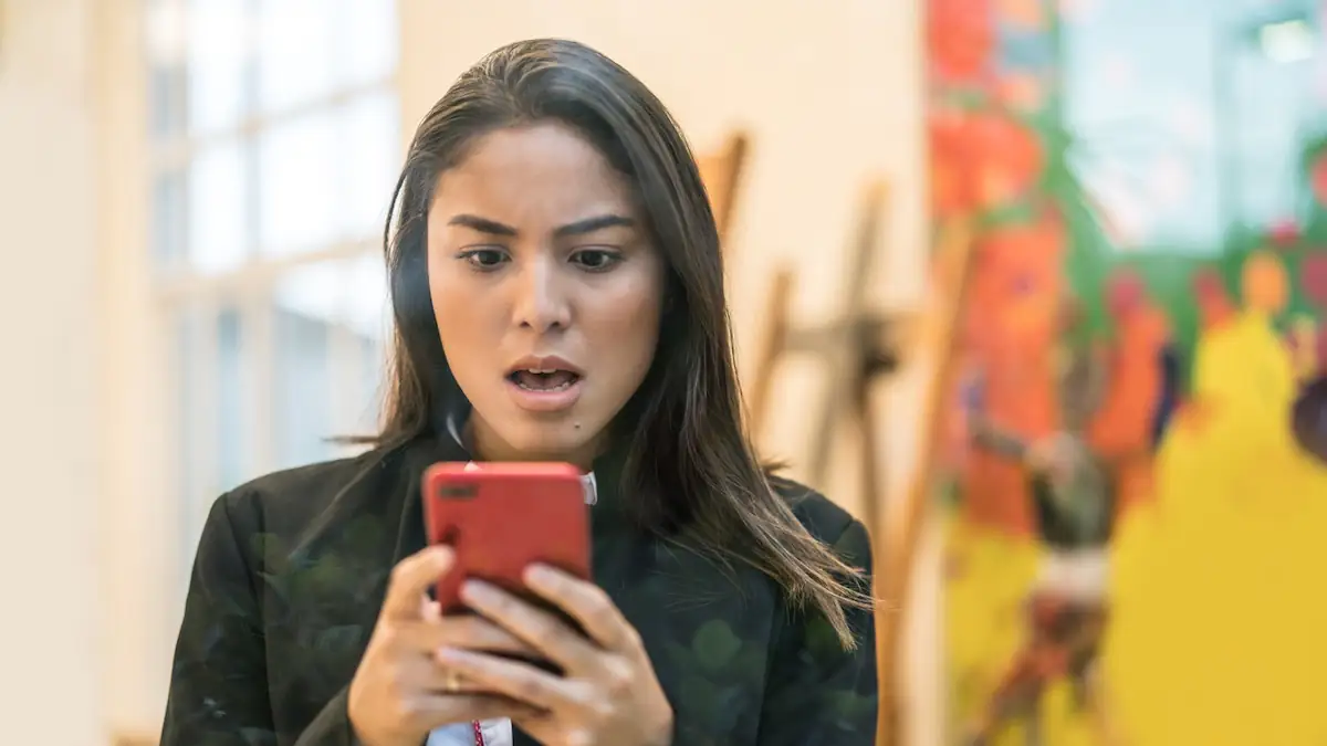 WhatsApp-Betrug: Frau schaut fassungslos auf ihr Smartphone