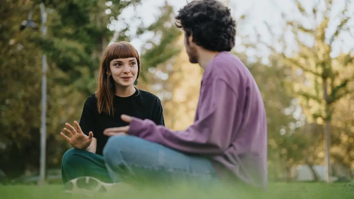 Ein junger Mann und eine junge Frau sitzen beim Small Talk nebeneinander