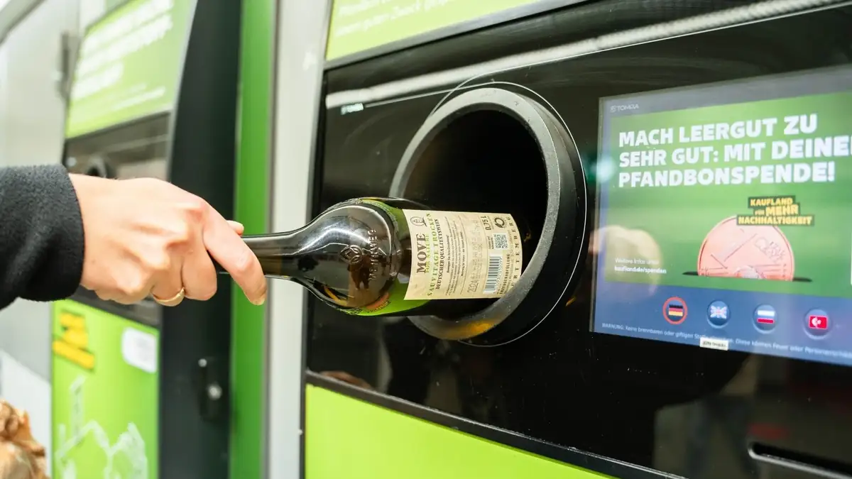 Jemand steckt eine Weinflasche mit Pfand in einen Automaten
