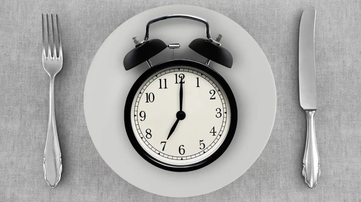 Spätes Abendessen: Leerer Teller, auf dem ein Wecker liegt, der 7 Uhr anzeigt