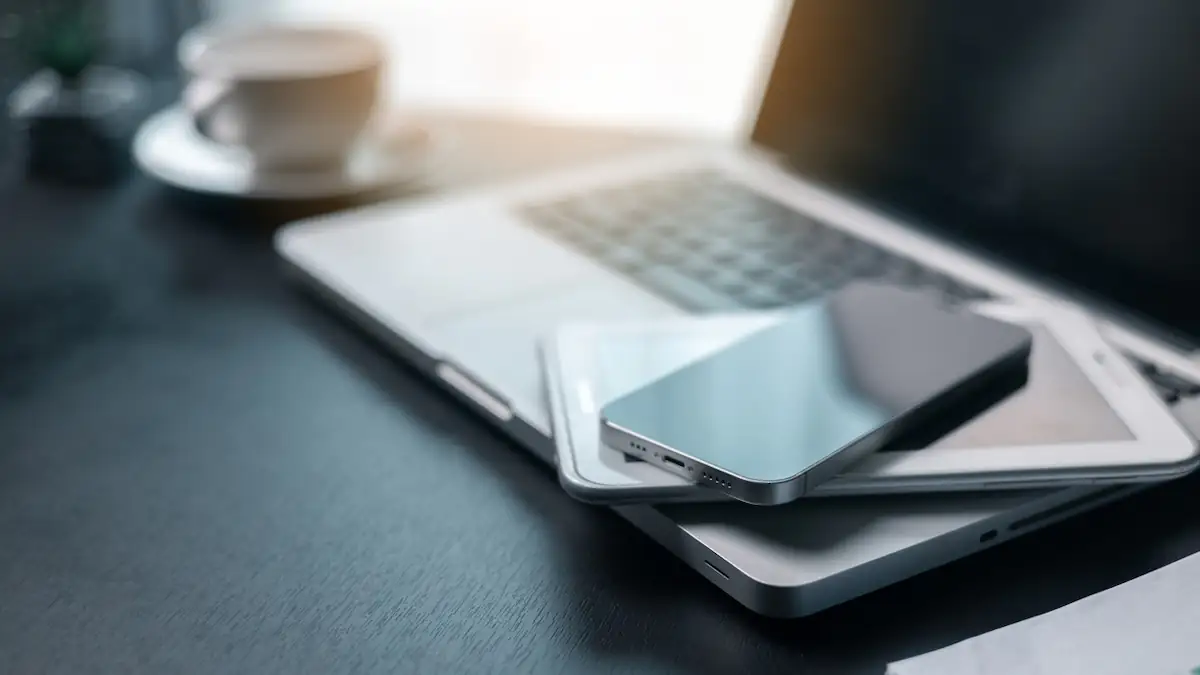 Altes Smartphone liegt auf einem Tablet, das wiederum auf einem aufgeklappten Laptop liegt