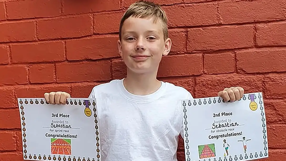 Verstorbener 12-jähriger Junge hält zwei Urkunden hoch